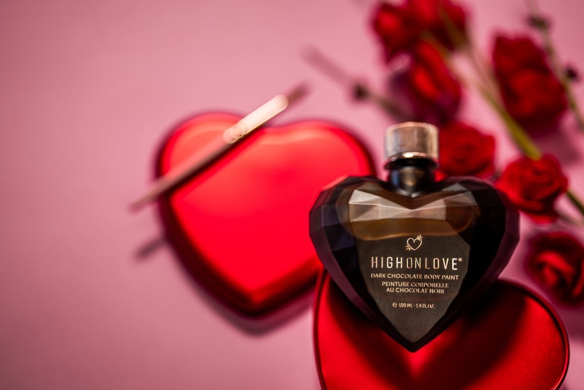 Heart-shaped High on Love perfume bottle with red heart and flowers on a pink background